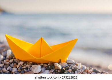 Yellow Paper Boat On The Beach At Sunset