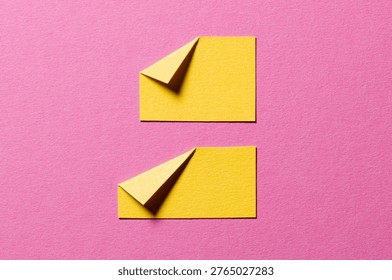 Yellow paper message notes or sheets with folded edge dog-ear earmark and copy space for text on pink background, top view flat lay conceptual desk backdrop