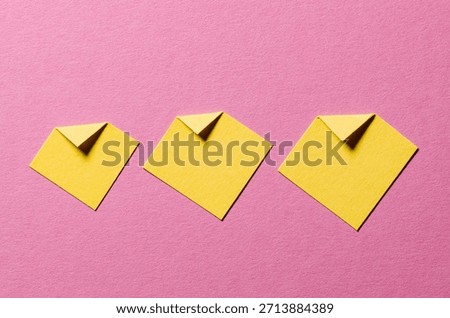 Yellow paper message notes or sheets with folded edge dog-ear earmark and copy space for text on pink background, top view flat lay desk backdrop