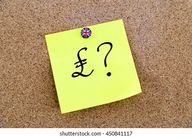 Yellow paper note pinned on cork board with Great Britain flag thumbtack, written Pound Sterling symbol and question mark, United Kingdom exit from European Union concept