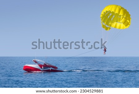 A yellow parasail wing pulled by a powerboat. Guy takes a selfie