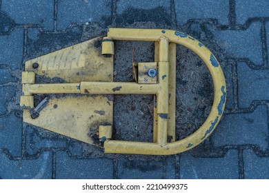 The Yellow Parking Blocker Is Bolted To The Cobblestone Road Around The Dirt The Parking Blocker Itself Is Dirty Photo From Above