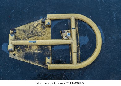 The Yellow Parking Blocker Is Bolted To The Cobblestone Road Around The Dirt The Parking Blocker Itself Is Dirty Photo From Above