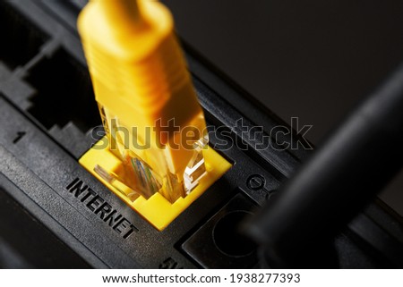 A yellow patch cord is inserted into the Wi-Fi port of the router to access the Internet. Internet connection via a wire with a router. Macro, close-up
