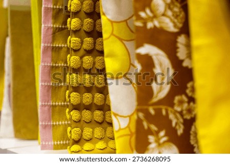 Yellow patterned fabrics hanging in textile store, decorative upholstery and curtain materials with texture and floral design, vibrant interior decor concept, close up fabric display