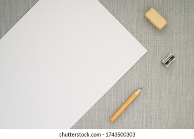 Yellow Pencil, Eraser, Sharpener And White Paper Sheet Lie On Grey Background. Flat Lay. No People. Copy Space. Mock Up. Artistic Tools, Drawing, Creativity, Design, Creativity And Object Concept