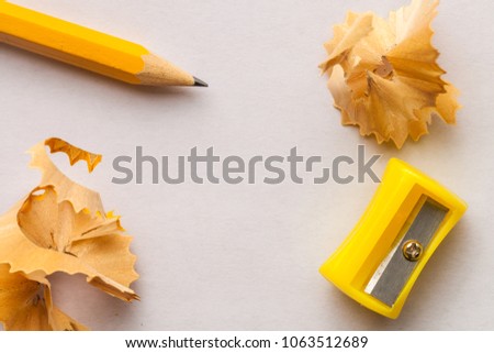 Yellow pencil, sharpner and shavings on white paper background with copy space