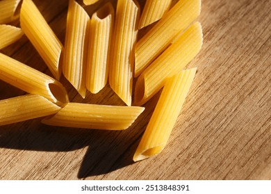 Yellow penne pasta texture. A detailed view capturing the ridges and structure of uncooked penne. Vibrant closeup macro shot of food. Italian cusine pattern. Food on wood background. - Powered by Shutterstock