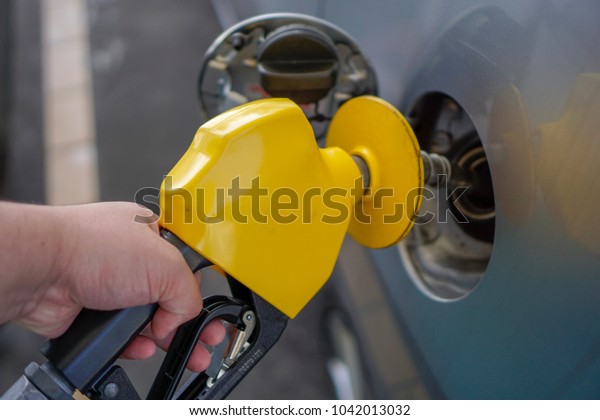 The yellow petrol pump handle at a petrol station.
Filling fuel in a car