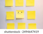 A yellow piece of paper with a sad face drawn on it is surrounde