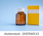 Yellow pill bottle and yellow pill box on blue background with copy space for text. Medical and health care concepts.