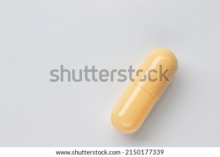 Yellow pill capsule on white background.