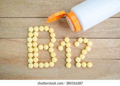Yellow pills forming shape to B12 alphabet on wood background
