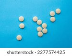 Yellow pills isolated on a blue background. Top view, flat lay.