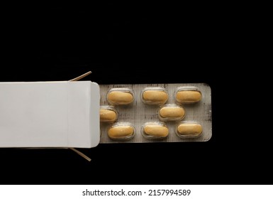 Yellow Pills In Open Box Isolated On Black  Background.  Image. Open Medicine Box With Two Blisters Of Pills 