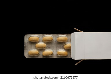 Yellow Pills In Open Box Isolated On Black  Background.  Image. Open Medicine Box With Two Blisters Of Pills 