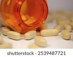 Yellow pills scattered on the table and open orange jar. In reality these are vitamin C tablets in a dosage of 1 gram