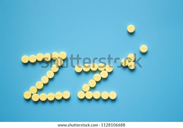 Yellow pills in Z shape. Sleeping pills on\
blue background