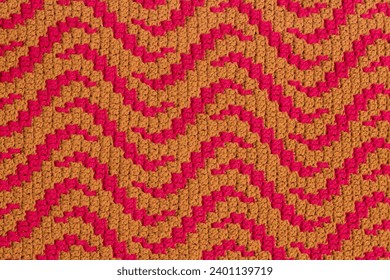Yellow pink crochet mosaic fabric with abstract pattern. Knitted background.