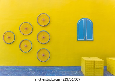 Yellow plain colour wall with blue colour window and bicycle rim. Selective focus with negative space. - Shutterstock ID 2237067039
