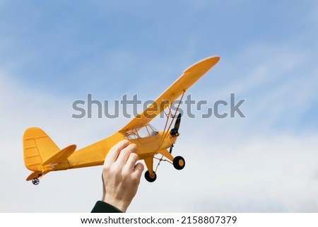Yellow plane above the sky. Man launching radio controlled airplane