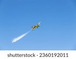 A yellow plane in flight in a blue sky