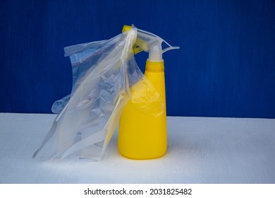 Yellow Plastic Bottle With Polyethylene Gloves On A White And Blue Background