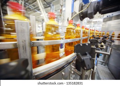 Yellow plastic bottles with light beer go on conveyor belt at large brewery.