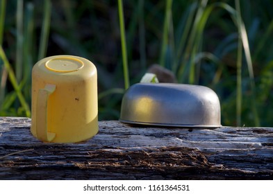 Yellow Plastic Coffee Cup And Metal Bowl Dry Upside Down On A Log On A Camping Trip, Spring Island, BC