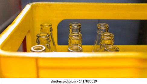 yellow plastic crate with several empty glass bottles inside