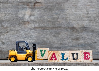 Yellow plastic forklift hold letter V to complete word value on wood background - Shutterstock ID 750819217