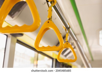 Yellow plastic handlebar in passenger bus. Pivoted grab handles in public transportation vehicles. Empty modern city bus with comfortable new handgrips.