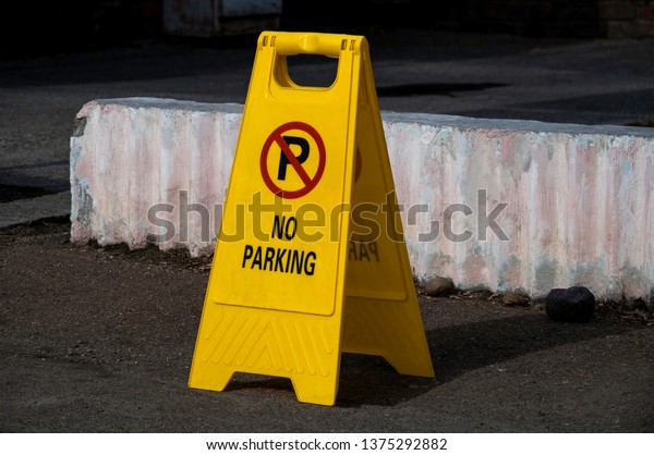 Yellow plastic sign\
prohibiting parking.