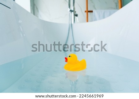 Yellow playful rubber duck float in the bathtub. Kids bath time concept. Funny toy for kits
