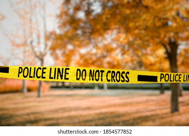 Yellow Police Tape Isolating Crime Scene. Blurred View Of Autumn City Park 