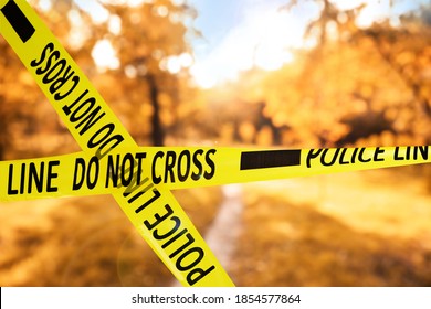 Yellow Police Tape Isolating Crime Scene. Blurred View Of Autumn Park 