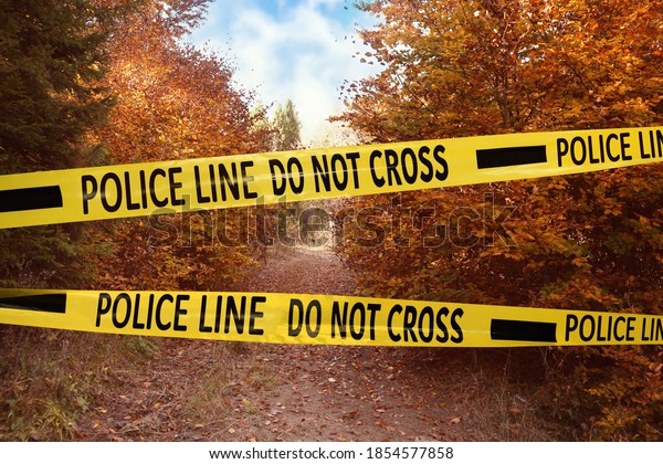 Yellow police tape isolating crime scene. Restricted\
area of autumn park 