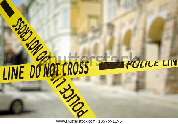 Yellow police tape isolating crime scene. Blurred\
view of city street