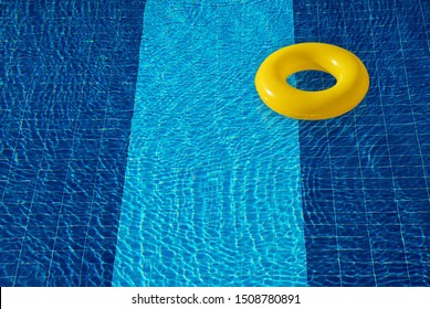 Yellow pool float, ring floating in a refreshing blue swimming pool