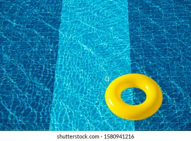 Yellow pool float, ring floating in a refreshing blue swimming pool