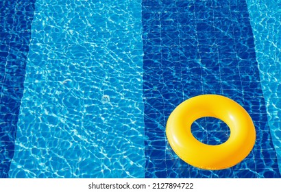 Yellow pool float, ring floating in a refreshing blue swimming pool