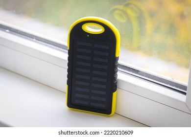 A yellow power bank with a solar battery during the day