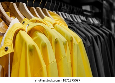 Yellow rain jackets hang on wooden hangers, close up. Yellow and gray fashion background. Trendy Colors of the year 2021 Yellow Illuminating and Ultimate gray 