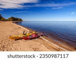 Yellow and red kayaks pulled up on the sandy beach on the south shore of Great Slave Lake near Hay River in Canada
