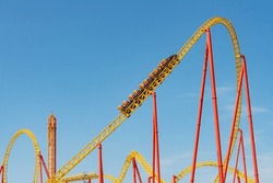 Yellow And Red Roller Coaster With Upturning Trolleys On A Turn And A Loop
