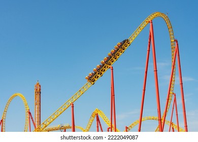Yellow and red roller coaster with upturning trolleys on a turn and a loop