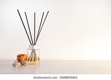 A yellow reed diffuser an dried flowers for interior decor or on top of a wooden table. In front of white wall.