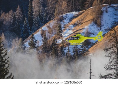 A Yellow Rescue Helicopter Is Taking Of In The Middle Of The Ski Slope Area In A Big Cloud Of Snow. Concept Of Helicopter Rescue On Snow Or Ski Slope.