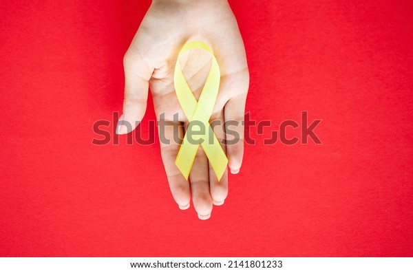 Yellow ribbon in\
hands, symbol Bladder\
cancer