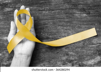 Yellow ribbon symbolic color for Sarcoma Bone cancer, Bladder cancer, Liver disease, Spina Bifida Awareness Month and suicide prevention on helping hand (isolated with clipping path)